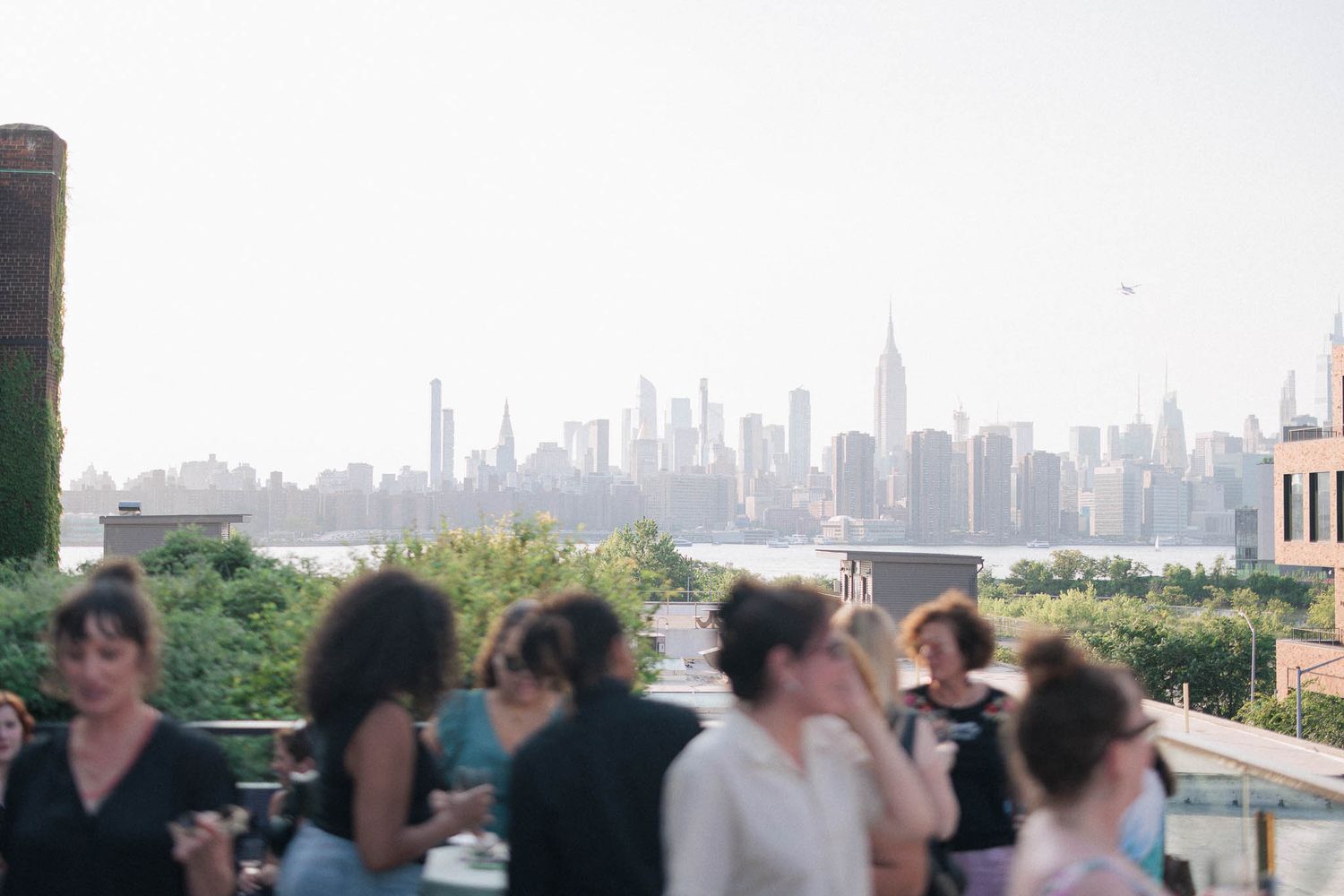 City skyline view from a rooftop venue with guests enjoying drinks and conversation.