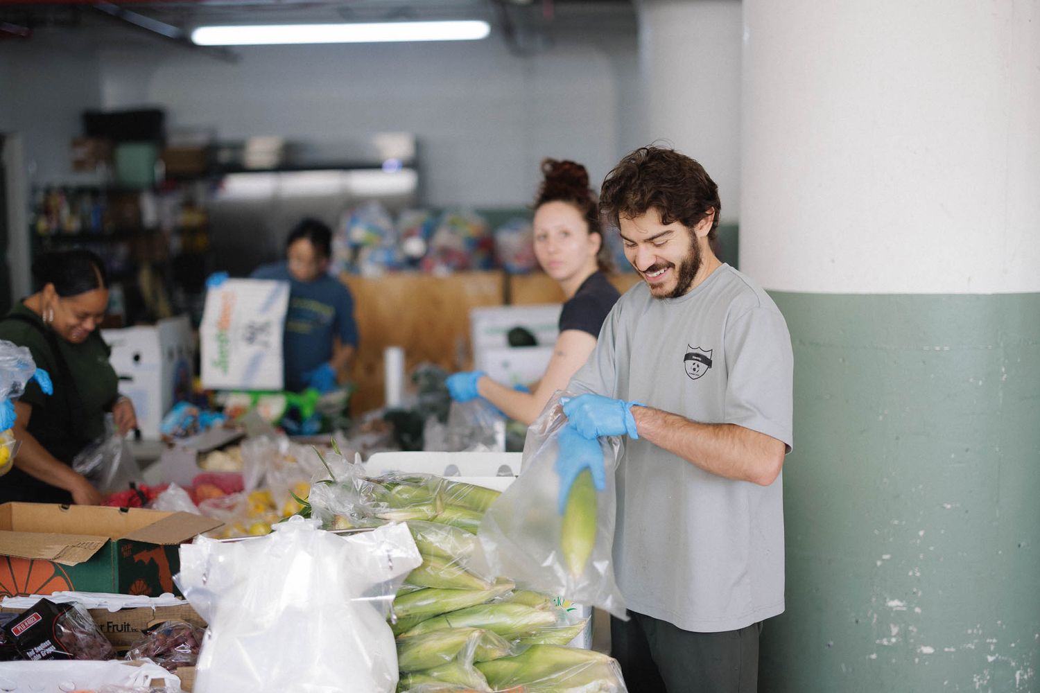 Workers pack fresh produce and groceries into bags at a food distribution center.