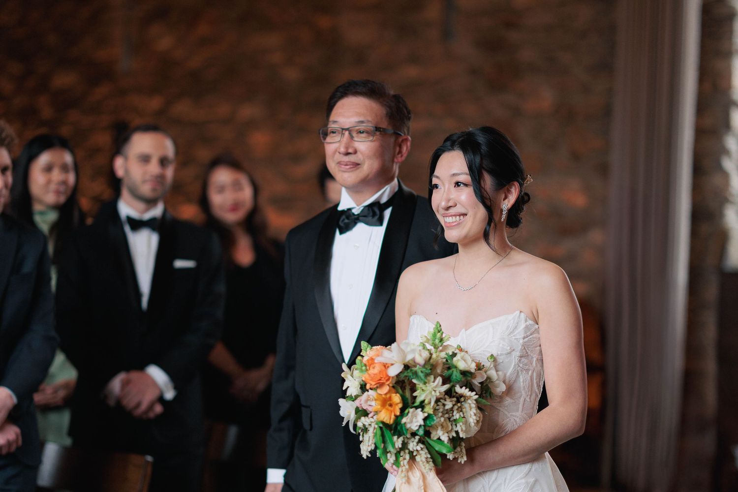 Wedding party gathering in rustic brick venue with formal attire.