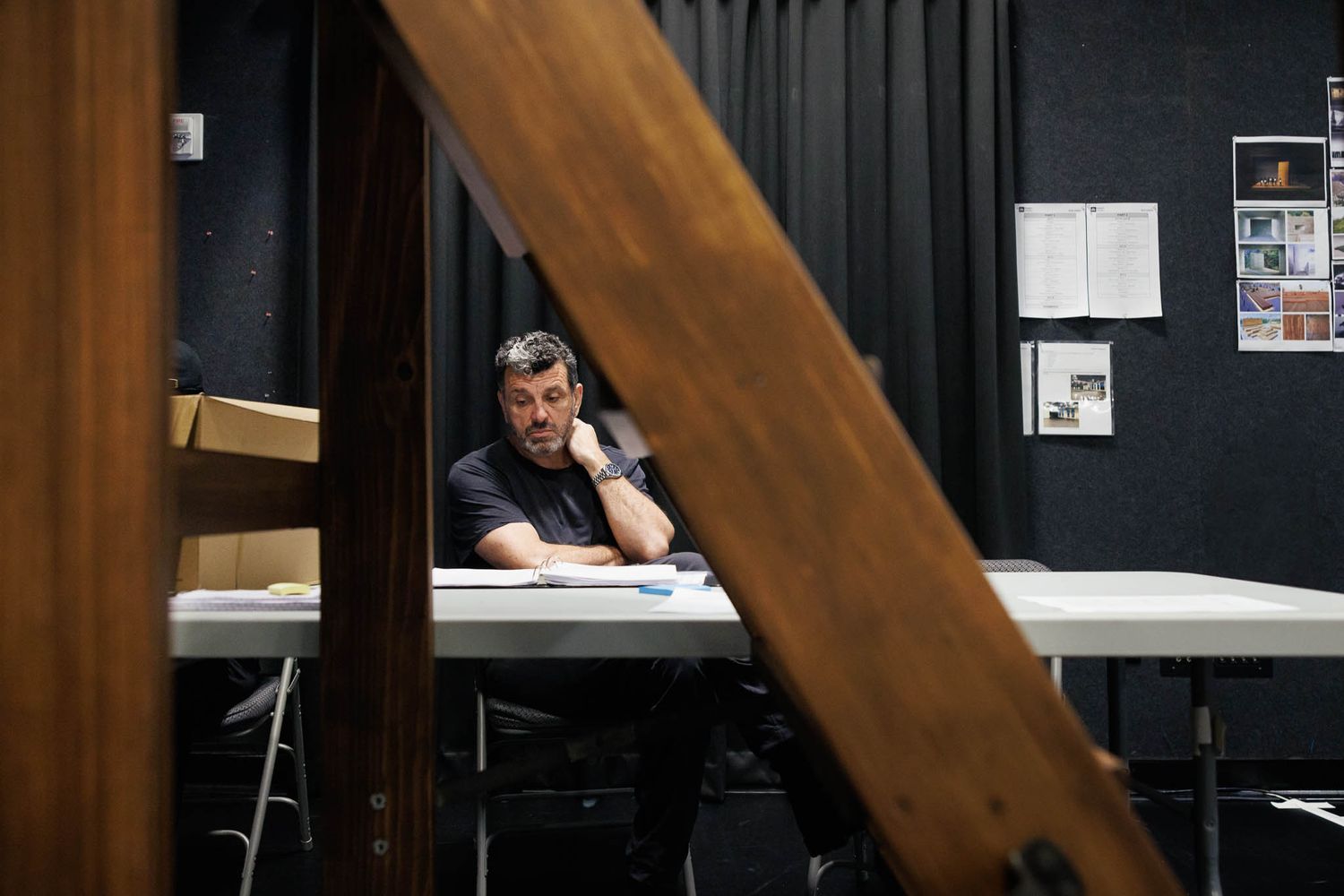Behind-the-scenes view of a theater workspace with wooden beam framing the composition.