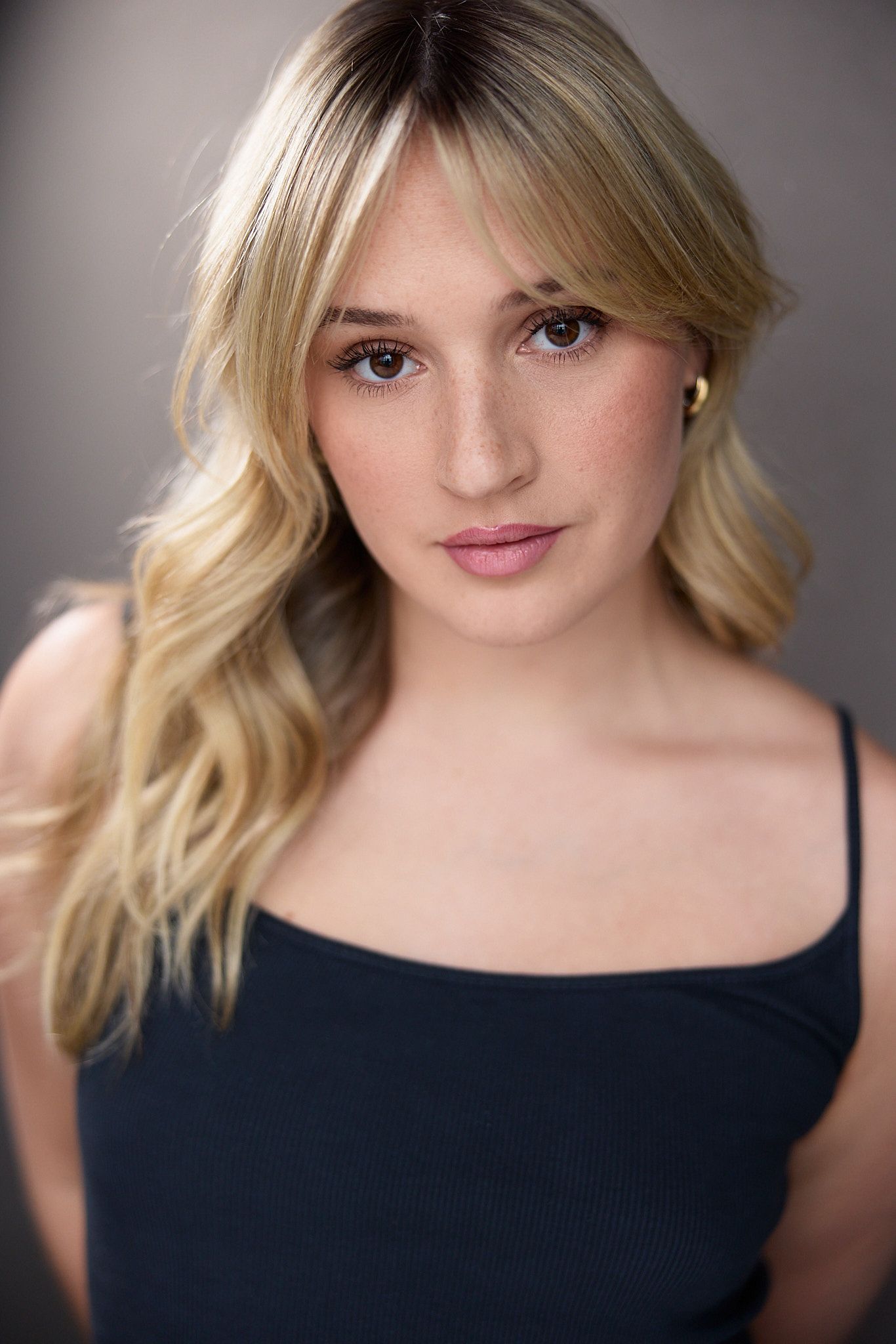 Professional headshot portrait series showing blonde hair and black top against neutral gray background.