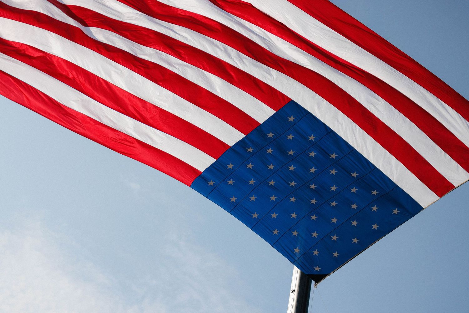 American flags wave against a bright blue sky on a sunny day, creating a patriotic display.