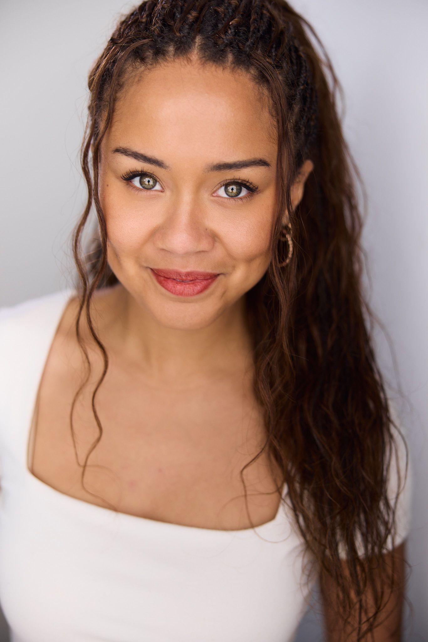 Studio portrait series showing joyful expressions against light gray background wearing a white top.