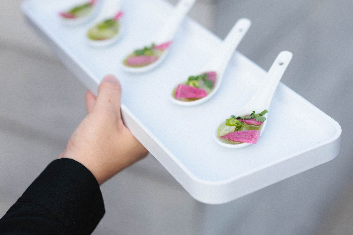 White serving trays with colorful appetizers being passed at an event.