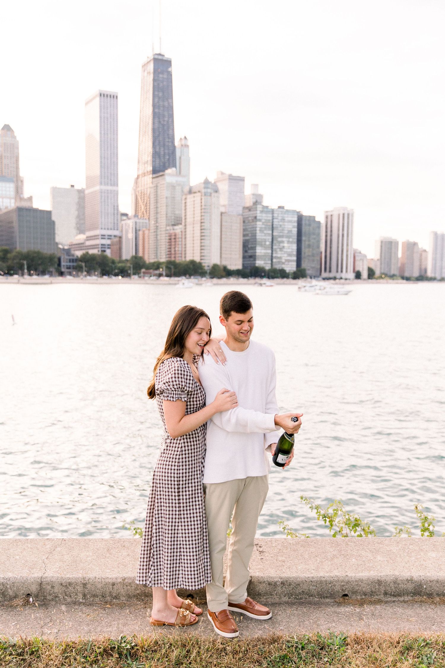 Couple celebrating with champagne by Lake Michigan with Chicago skyline backdrop on a sunny day.