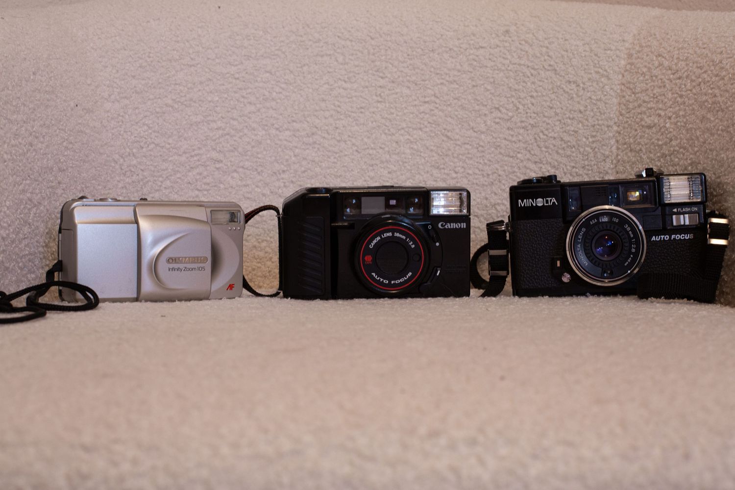 Three 35mm point and shoot film cameras.