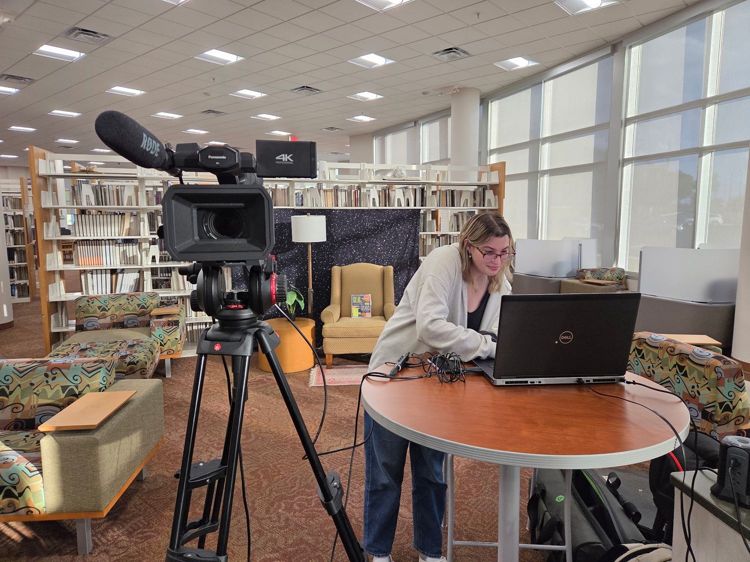 A person with a camera and laptop operating a live stream.