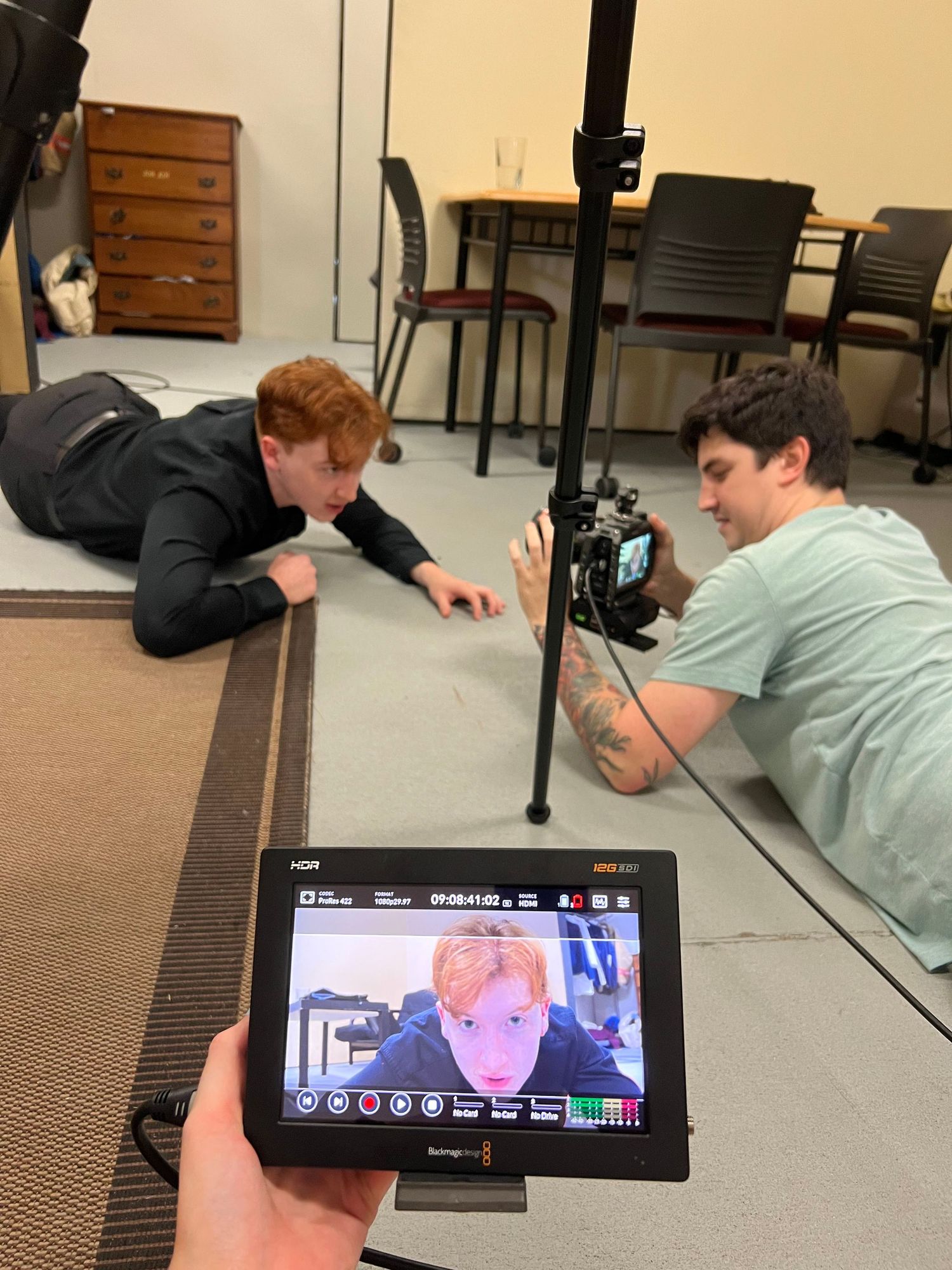 Camera setup for low-angle filming with monitor display visible in foreground.