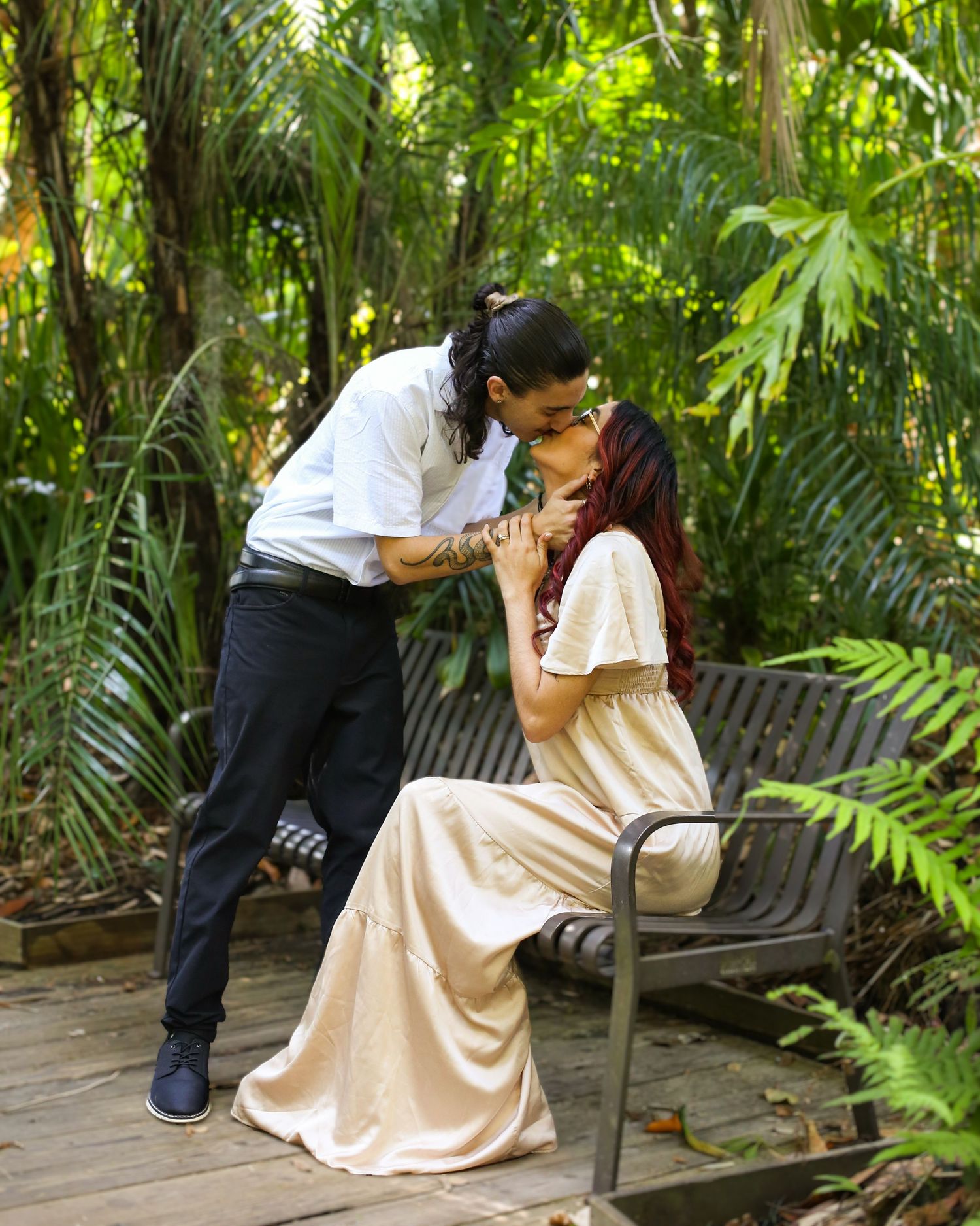 Intimate moment shared on a wooden bench surrounded by tropical foliage at Harry P. Leu Gardens in Florida.