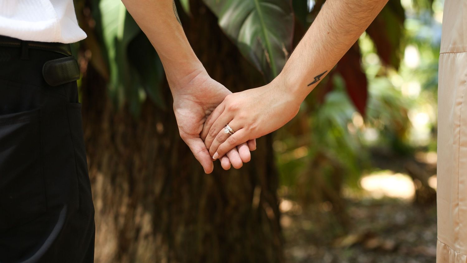 Engaged couple holds hand to show off engagement ring at Harry P. Leu Gardens in Florida.