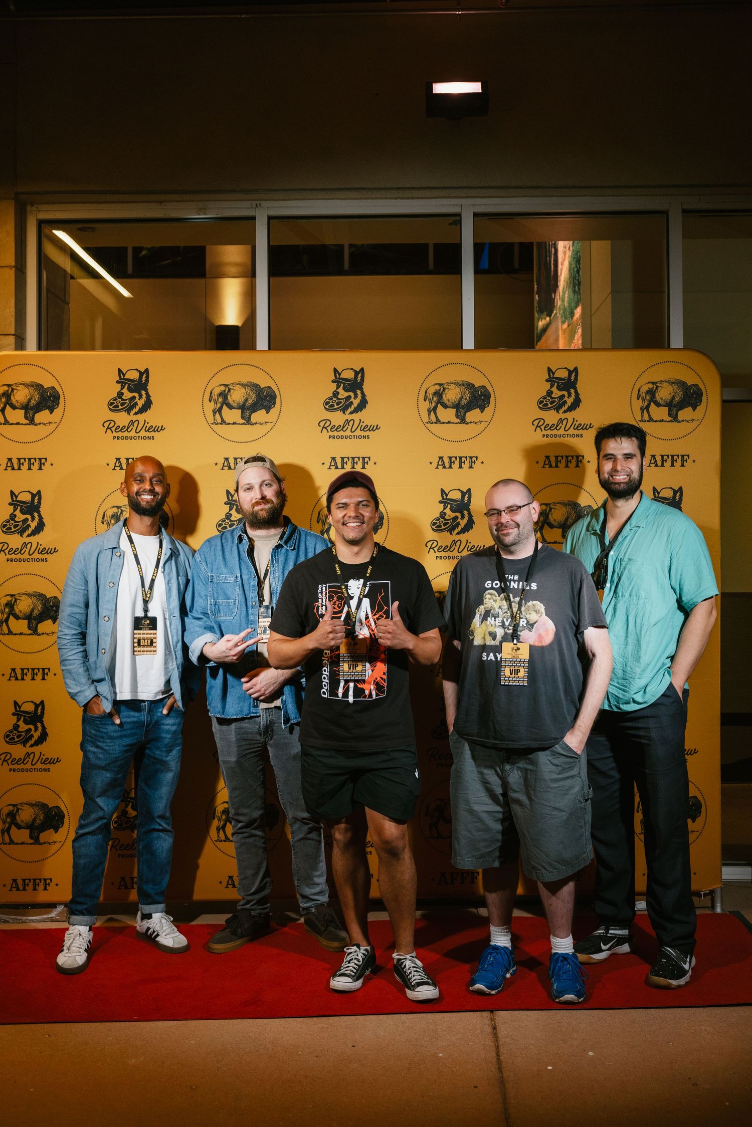 Group of people posing against a backdrop with bull and wolf logos at a film festival event.