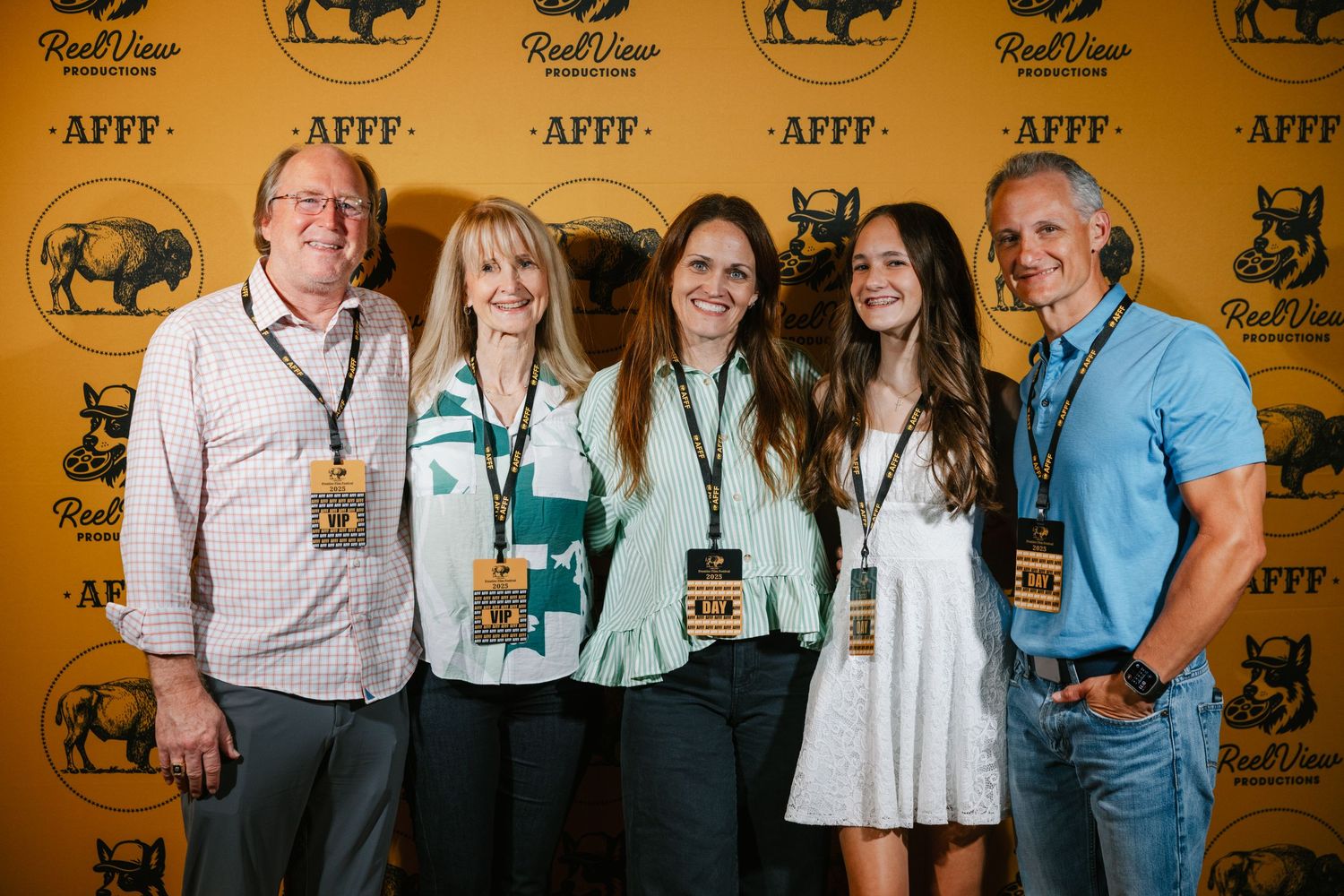 Group of people posing for photos in front of a yellow backdrop with black buffalo logos at an awards event.