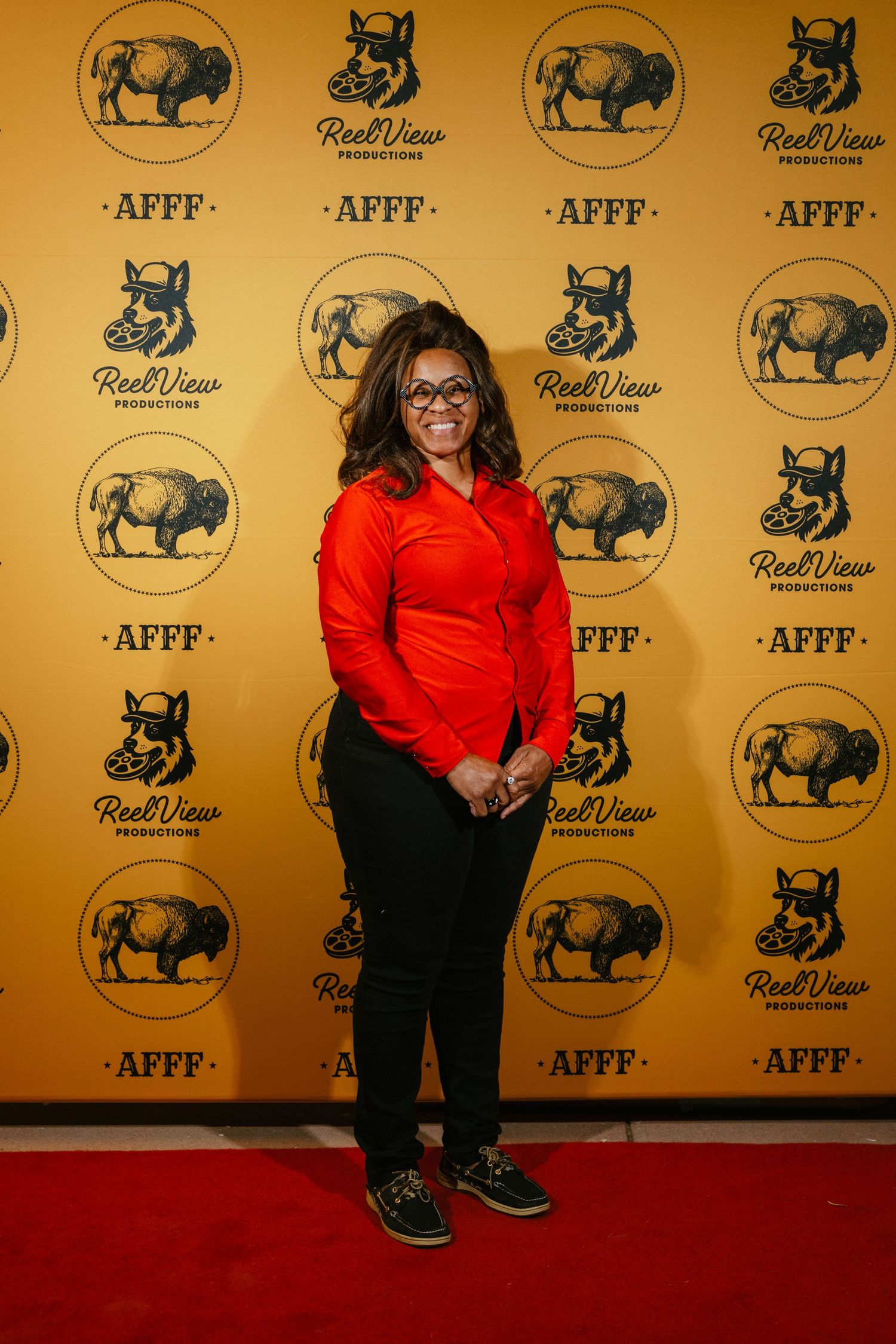 Person in a bright red top and black pants poses against a branded step-and-repeat wall with bull logos and AFFF text.