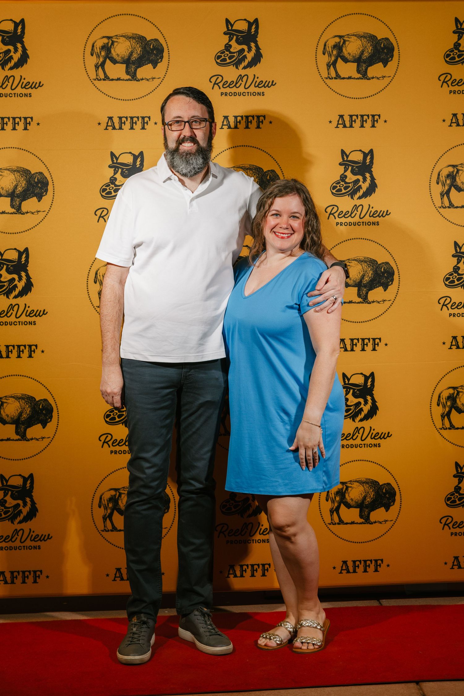 Guests pose for photos on a red carpet at an event with yellow backdrop featuring buffalo logos.