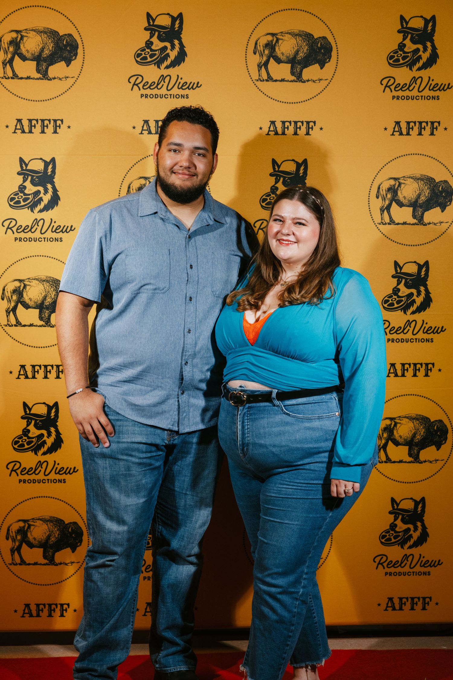 Couples posing in front of a yellow backdrop with bull and wolf logos at a film festival.
