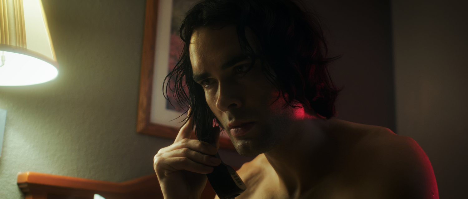 Intense young man holding a gun in a dimly lit room with dramatic lighting in a cinematic scene.