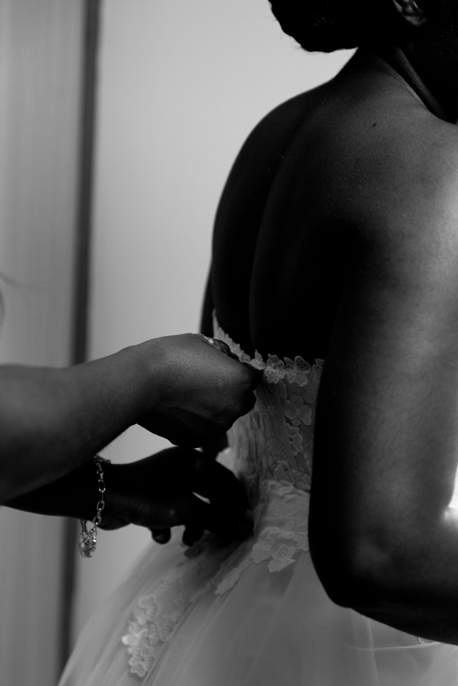 Close-up of bride’s hands fasteningher gown before wedding