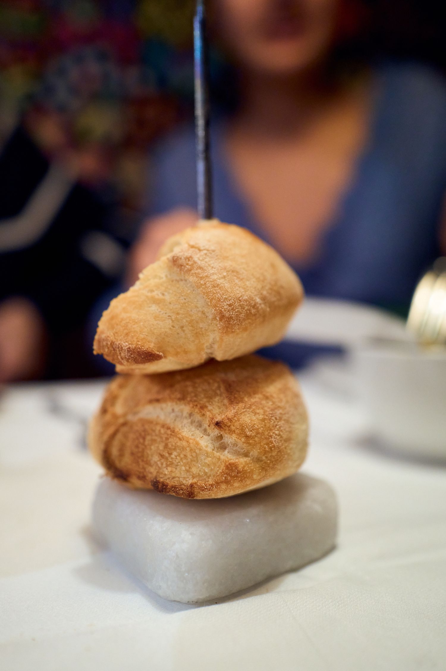 Fresh baked bread rolls stacked on a white stone platform.