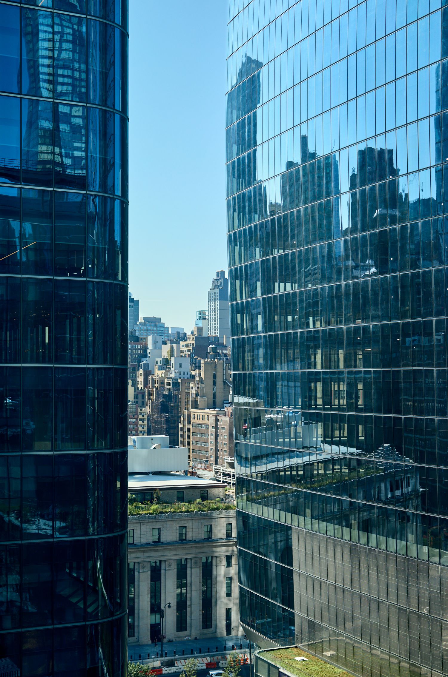 Glass skyscraper facades reflecting cityscape and blue sky in downtown business district.