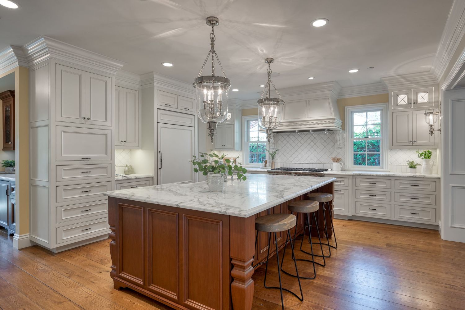 White kitchen with large center island, pendant lighting, and traditional wood cabinetry.