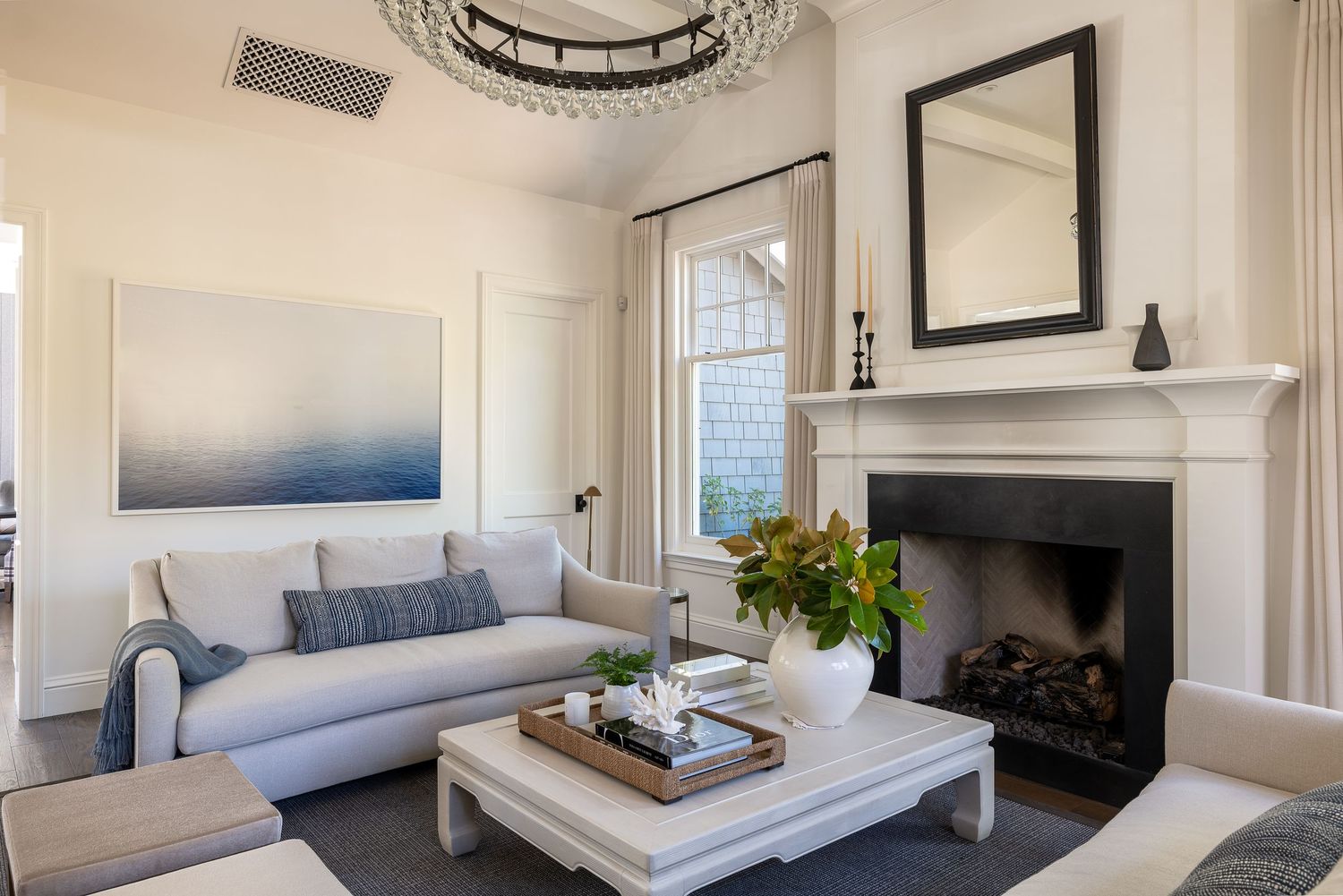 Modern coastal living room with white sofa, blue accents, and elegant fireplace.