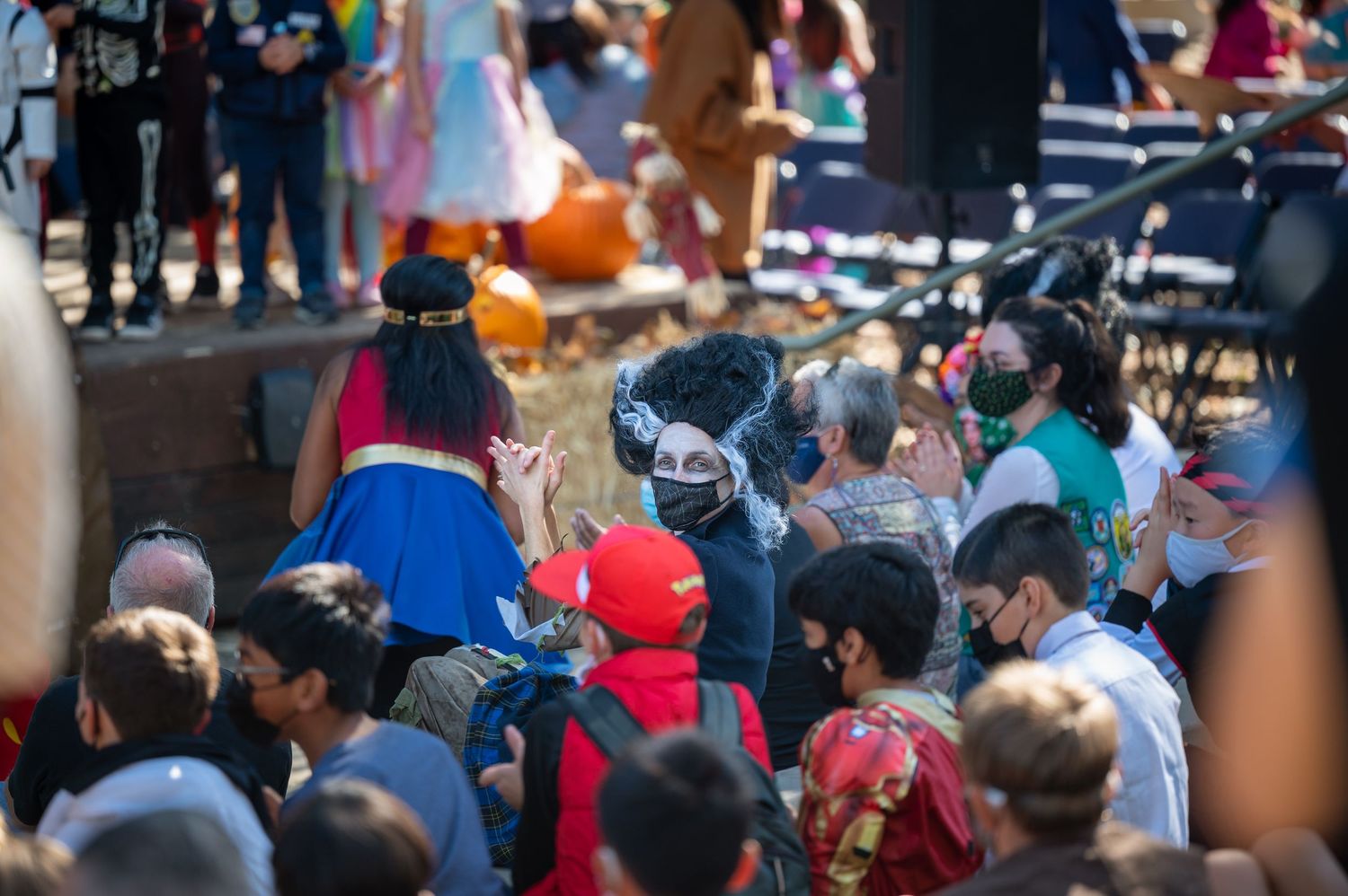 A crowded outdoor event with people wearing colorful clothing and hats in bright sunlight.