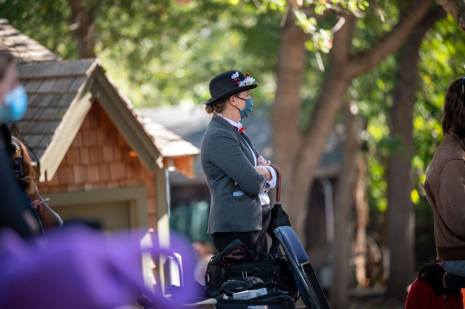 Person in uniform stands outdoors near wooden structures.
