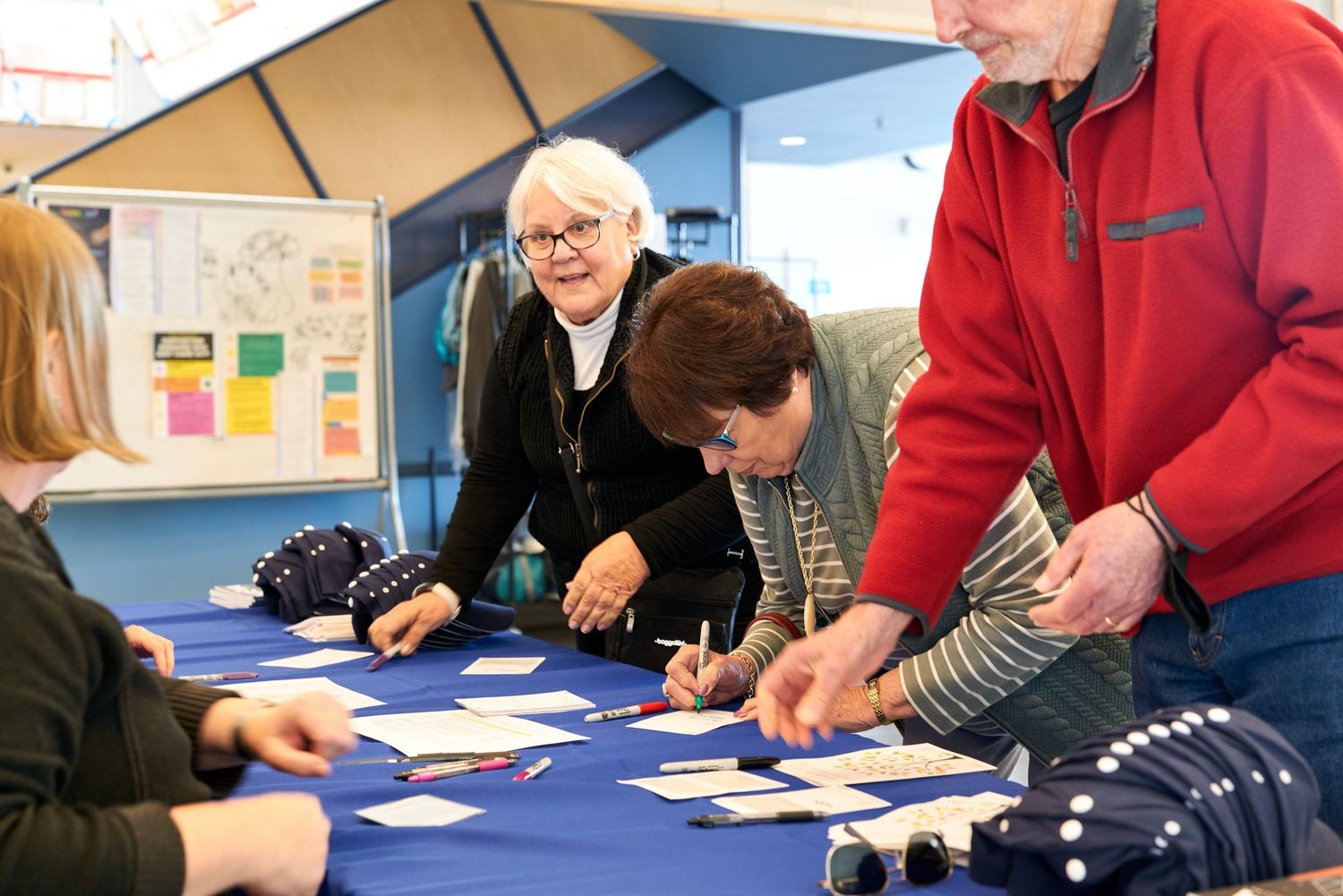 Several people gathered around a table playing cards or doing an activity at a community event.