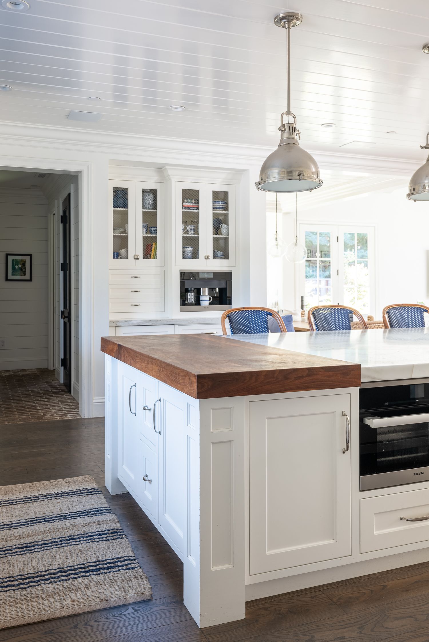 White kitchen island with butcher block top and pendant lights in modern farmhouse style room.