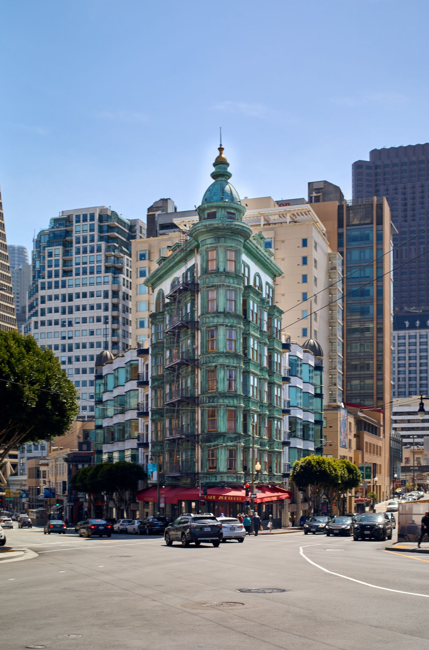 Historic green-tinted Sentinel Building in San Francisco surrounded by modern skyscrapers.