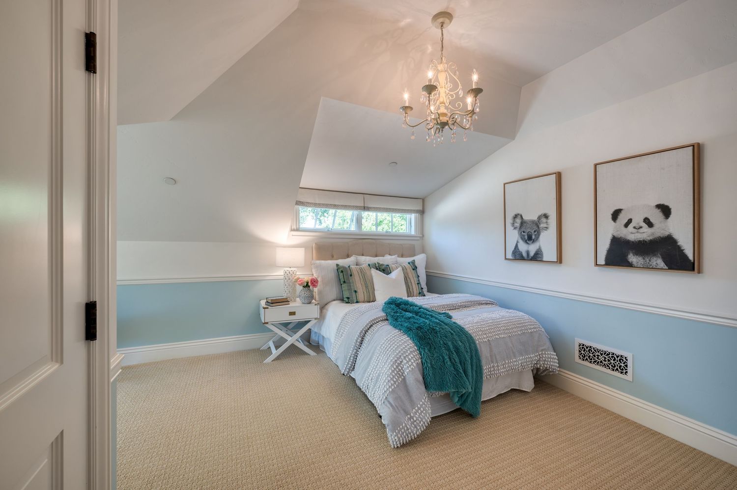 Bright attic bedroom with pale blue walls, panda artwork, and crystal chandelier.