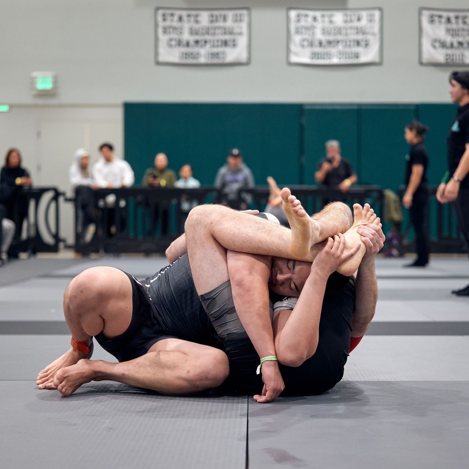 Two athletes grappling on the mat during an intense Brazilian jiu-jitsu competition match.