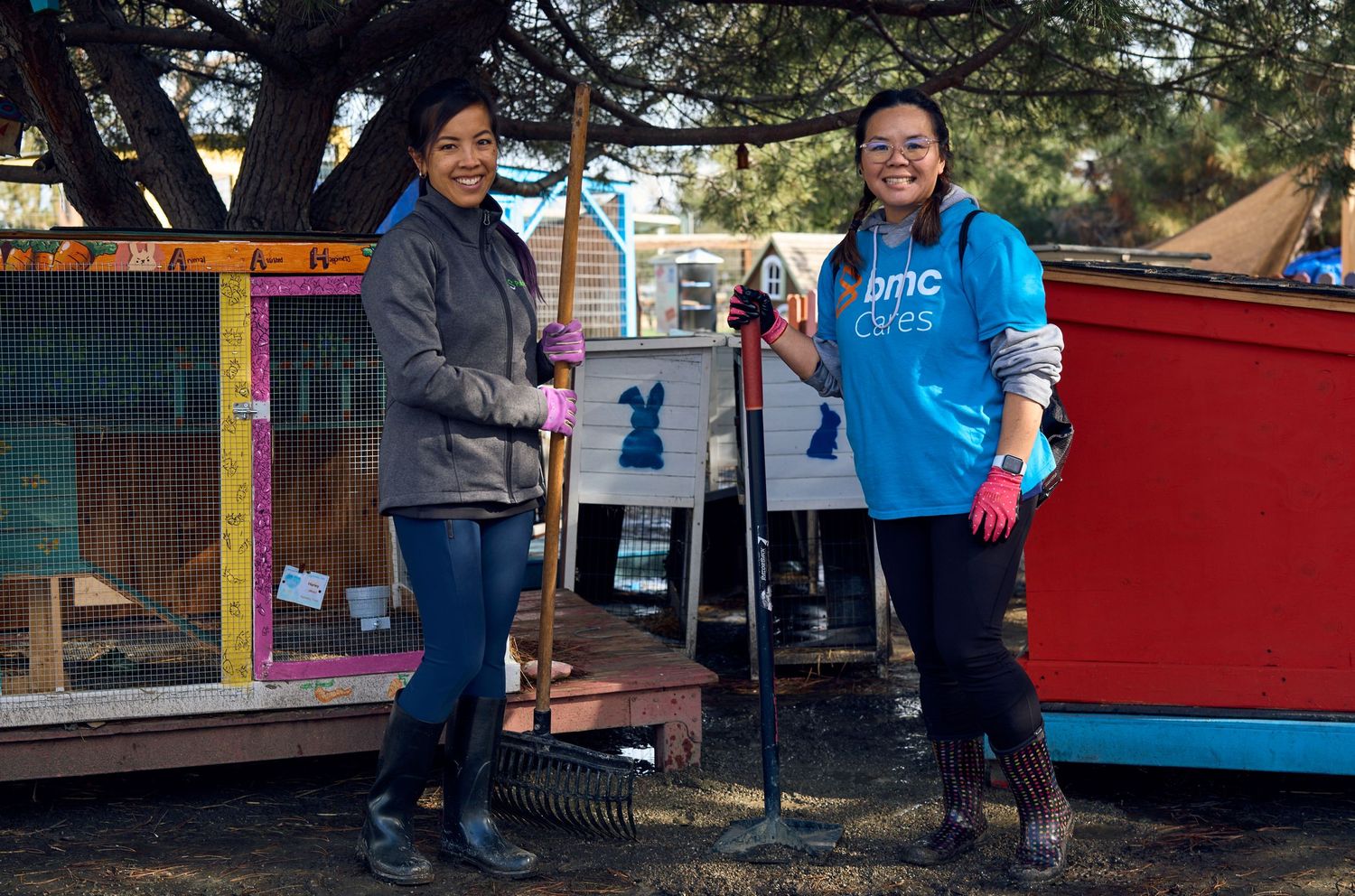 Two volunteers working together outdoors near colorful outdoor structures.