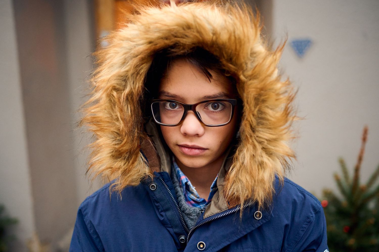 Person wearing glasses and fur-trimmed blue parka hood.