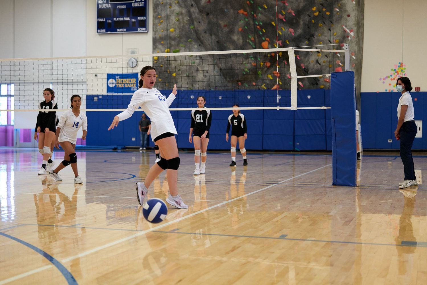 Player jumping to spike volleyball during competitive indoor match.