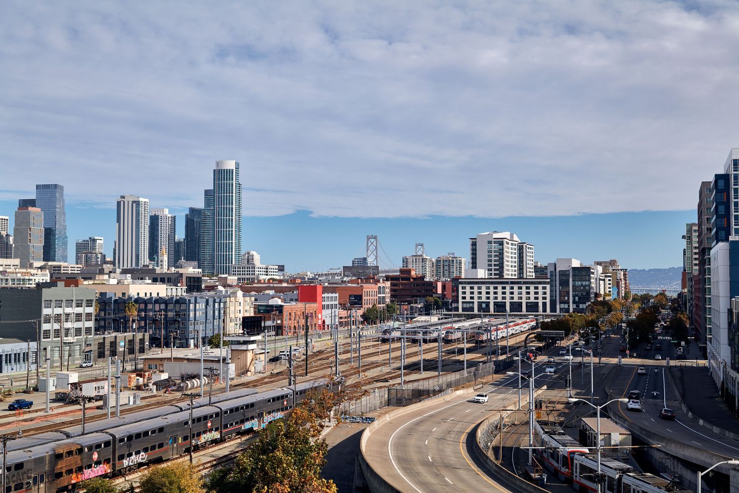 Modern city skyline with curved highway and railway tracks leading into downtown.