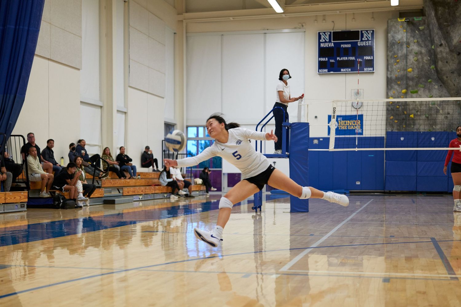 A volleyball player dives to save the ball during an indoor match.