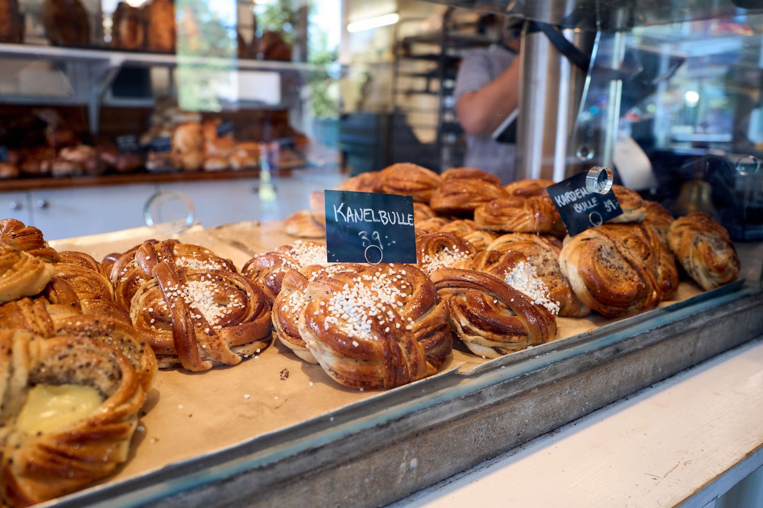 Fresh baked pretzel rolls and pastries displayed in a bakery case.