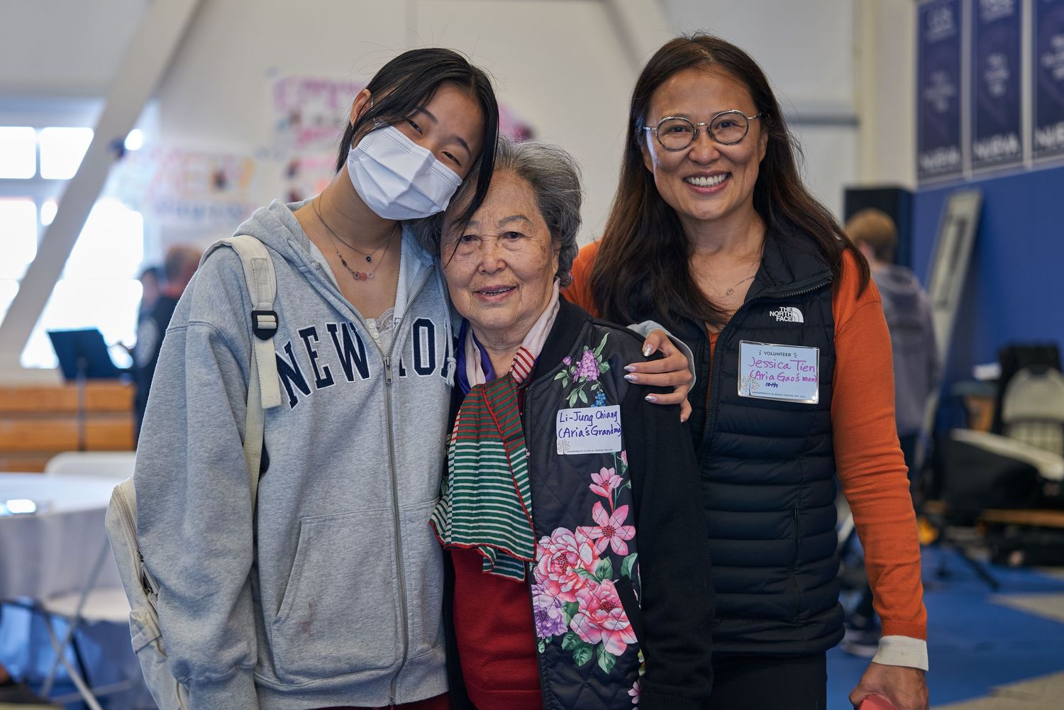 Three individuals sharing a warm moment at community event wearing casual attire.