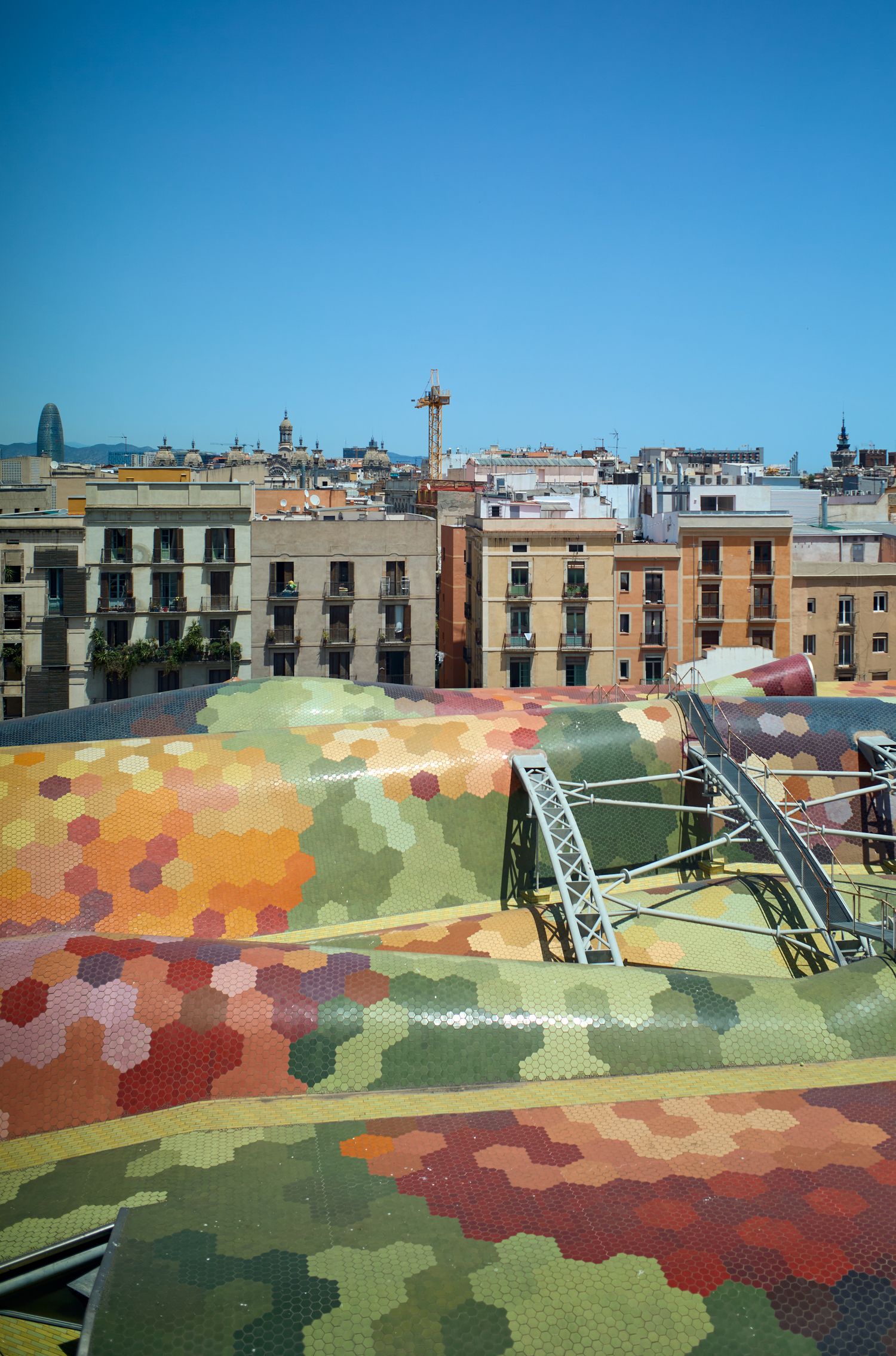 Colorful patterned rooftop terrace overlooking traditional European city buildings and architecture.