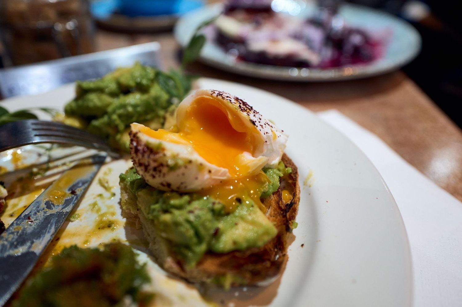 Avocado toast topped with a perfectly poached egg with runny yolk.