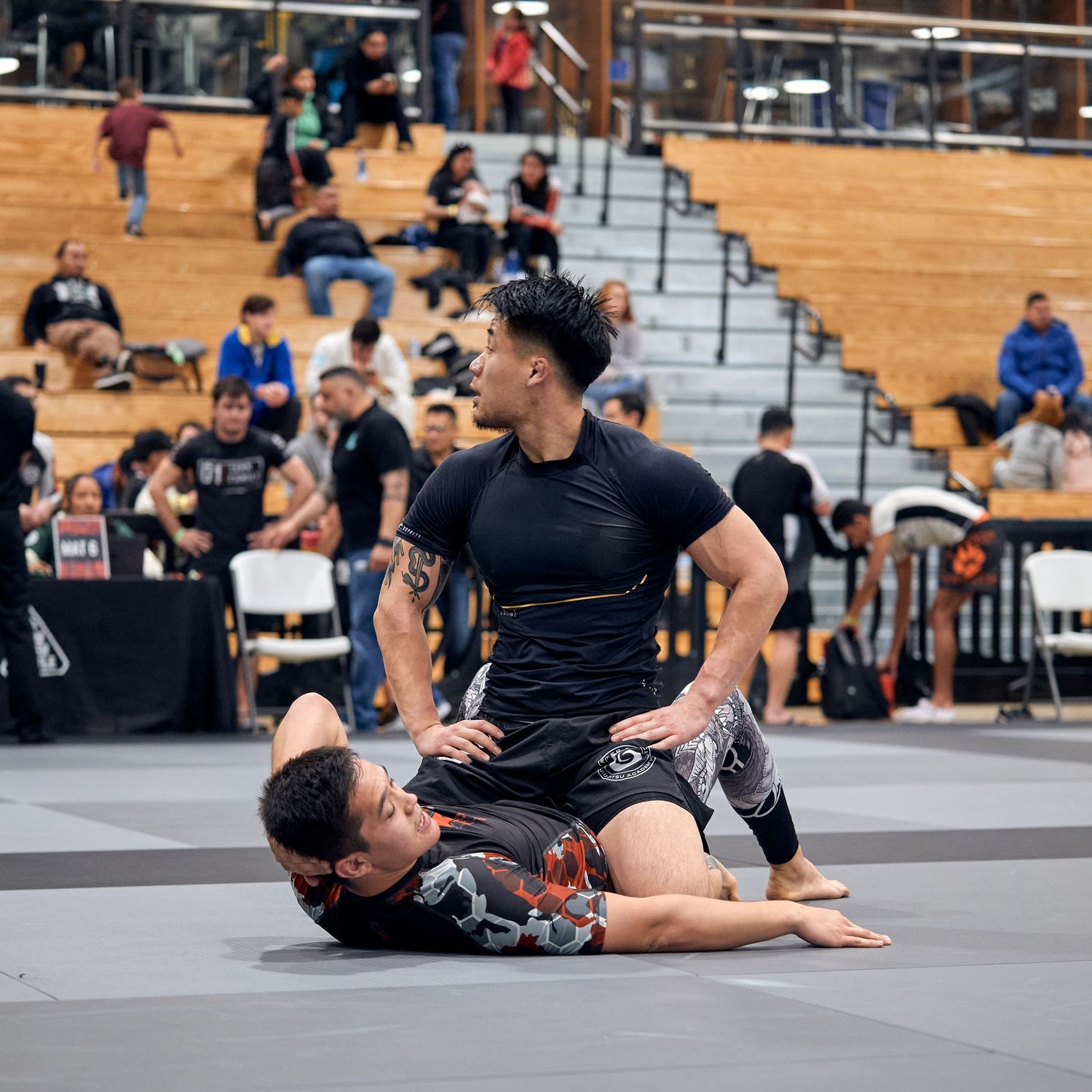 Two martial artists engaged in ground combat during a competitive match.