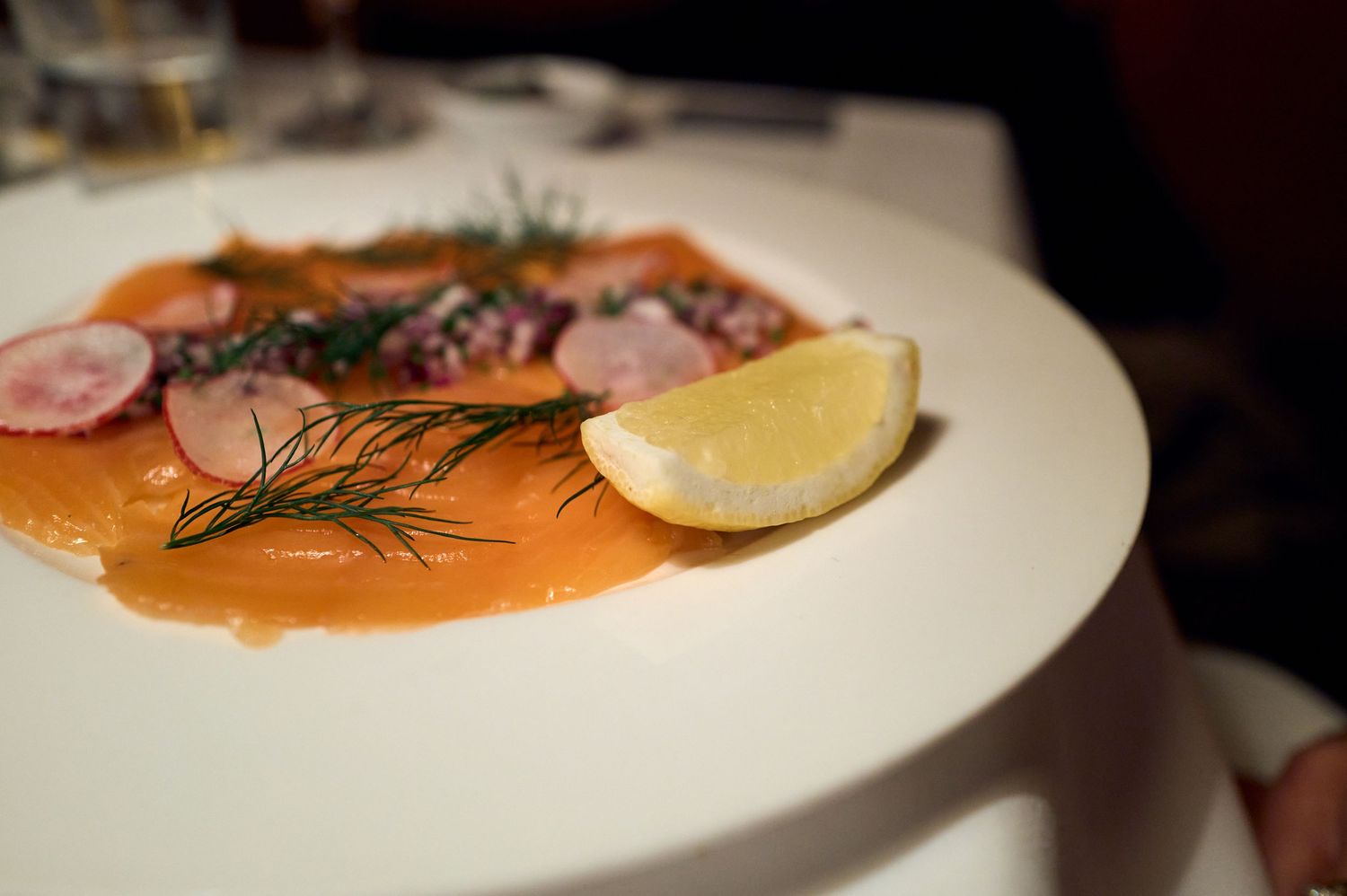 Elegant plate of smoked salmon garnished with dill and lemon wedge.