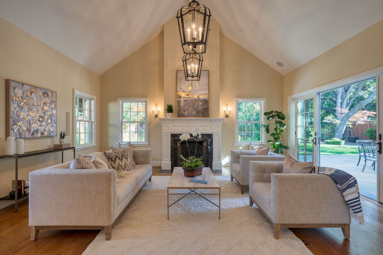 Spacious living room with cathedral ceiling, lantern chandelier, and symmetrical furniture arrangement.
