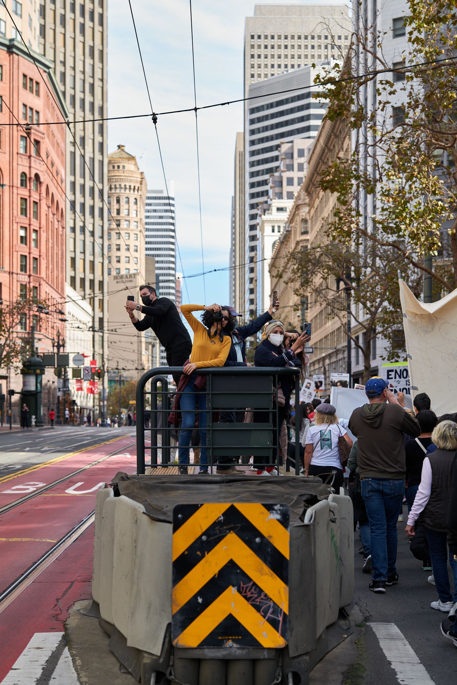 People standing on a maintenance vehicle in a city street with tall buildings in the background.
