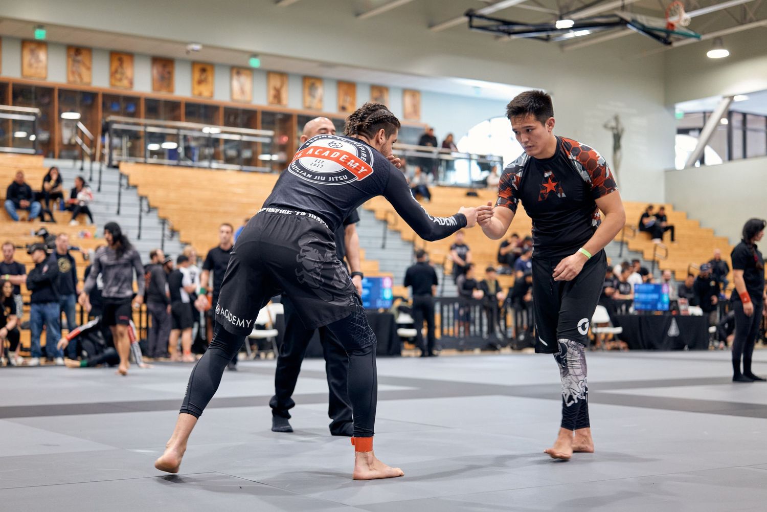 Competitors in black gis square off during a martial arts tournament.