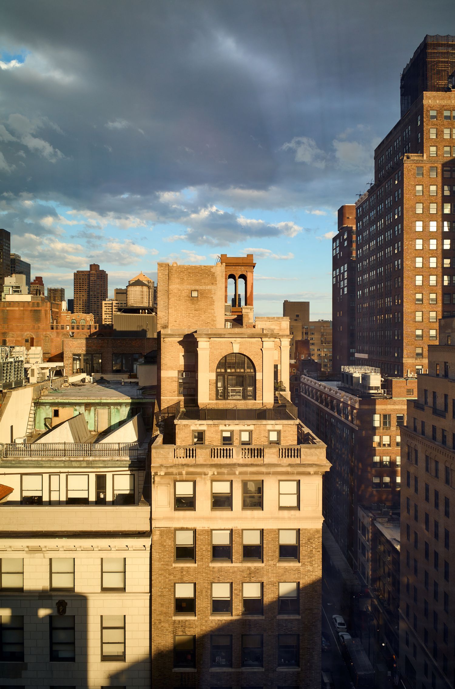 Historic apartment buildings with architectural details and rooftop structures in an urban neighborhood at sunset.
