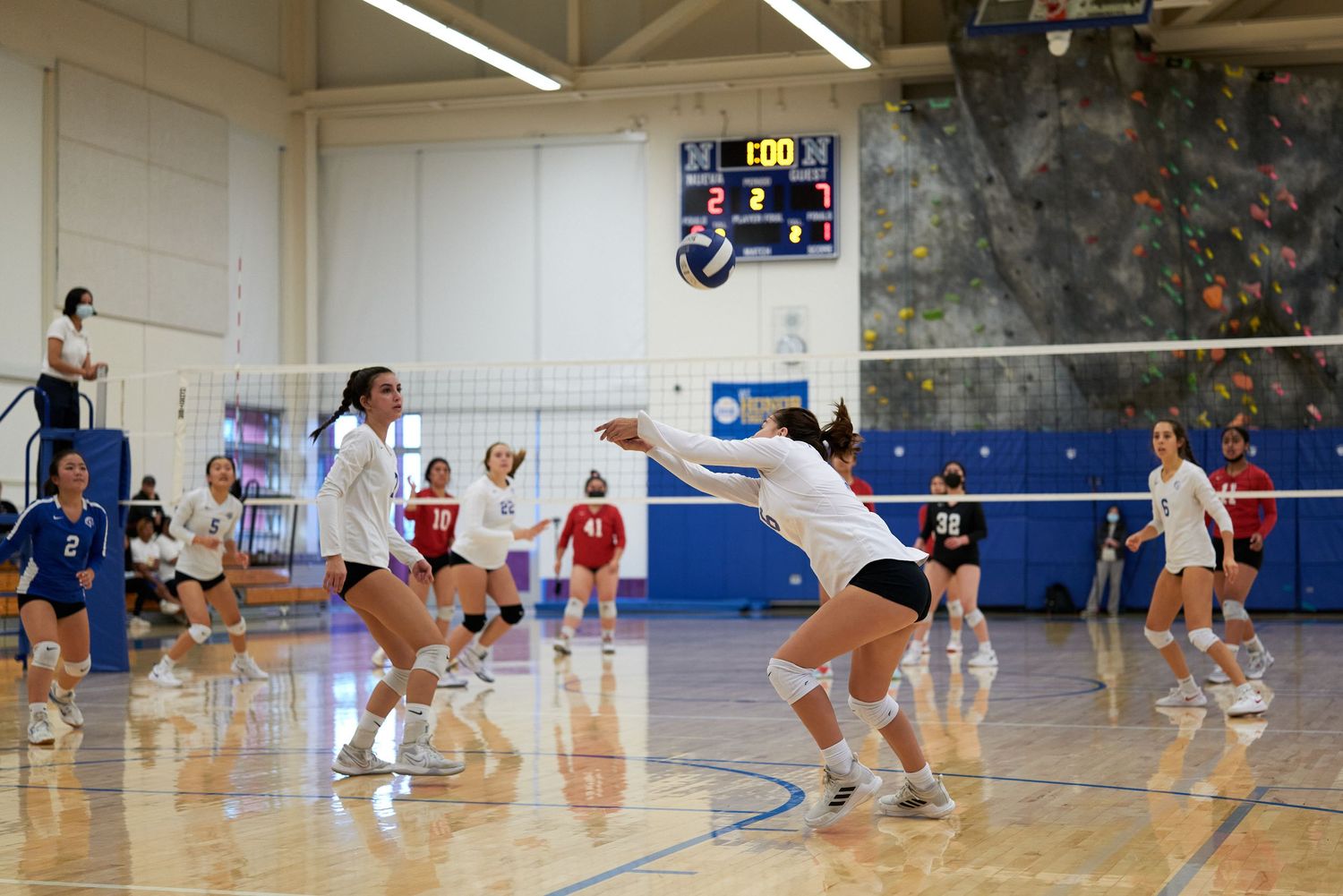 Players dive and jump for the volleyball during an intense indoor match.