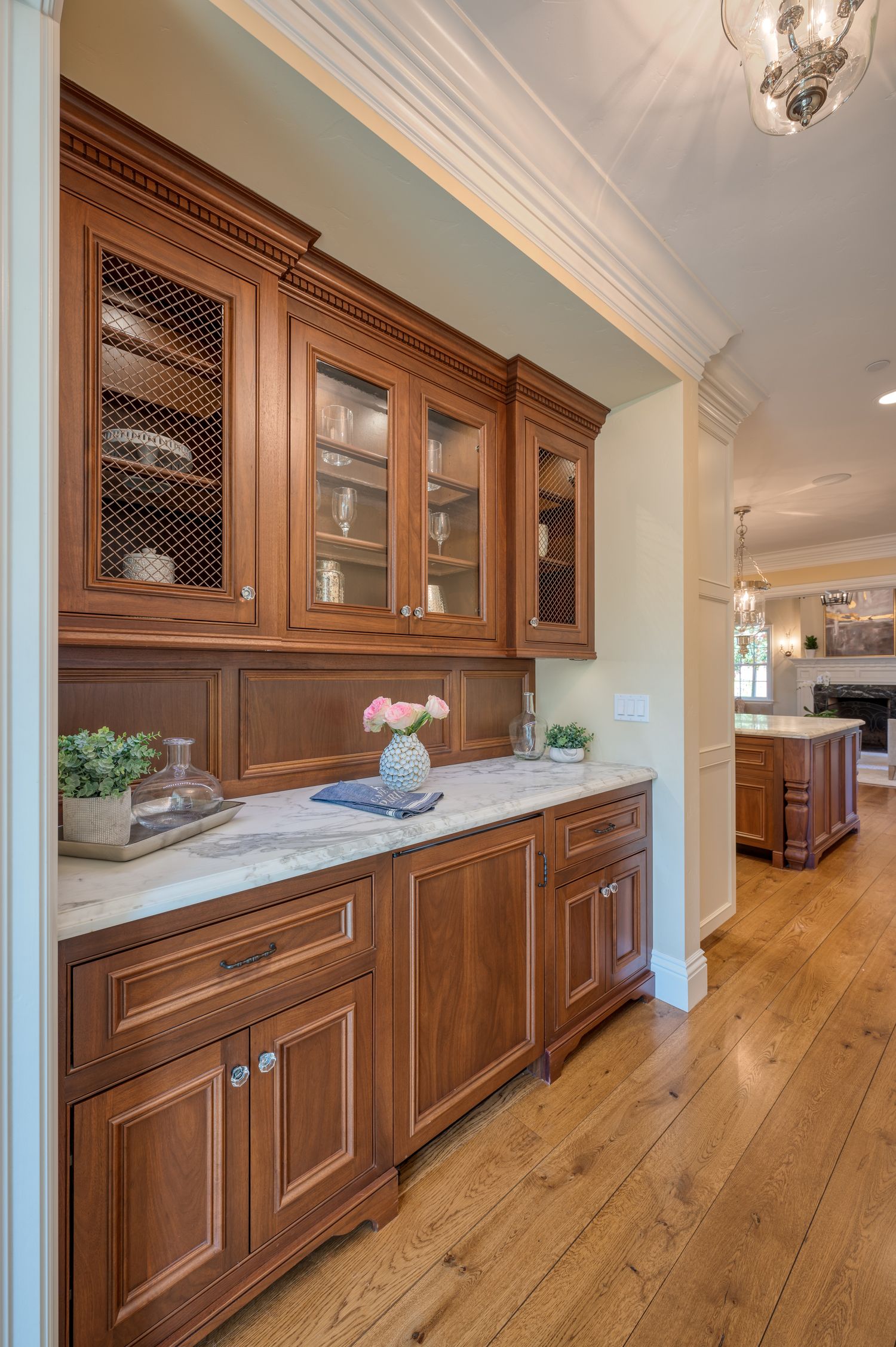Custom butler's pantry featuring wood cabinetry, glass doors, and marble countertop.