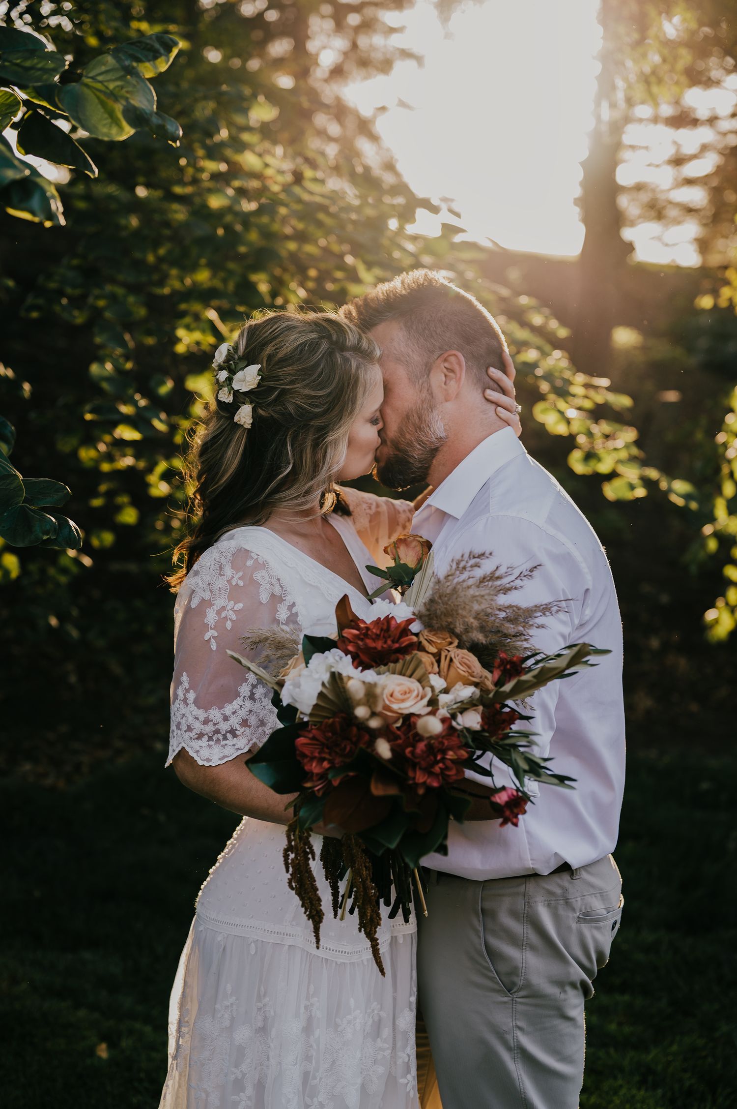 Newlywed couple embraces outdoors in golden sunset lighting during intimate wedding photo session.